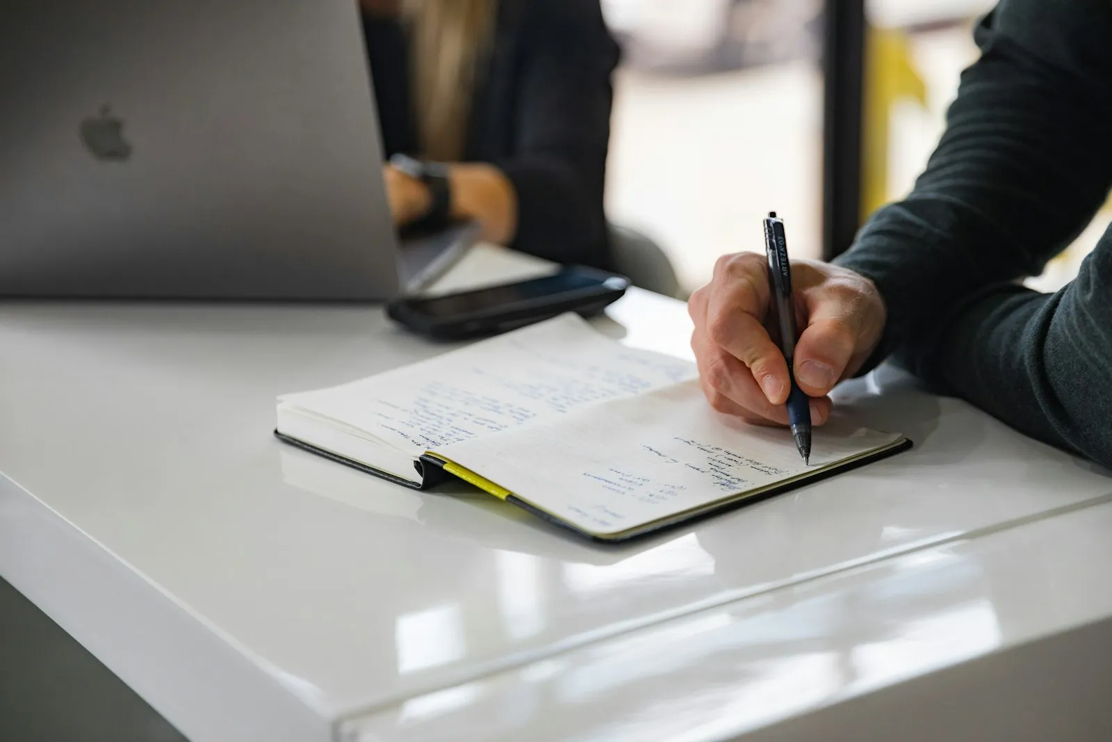 person holding on red pen while writing on book
